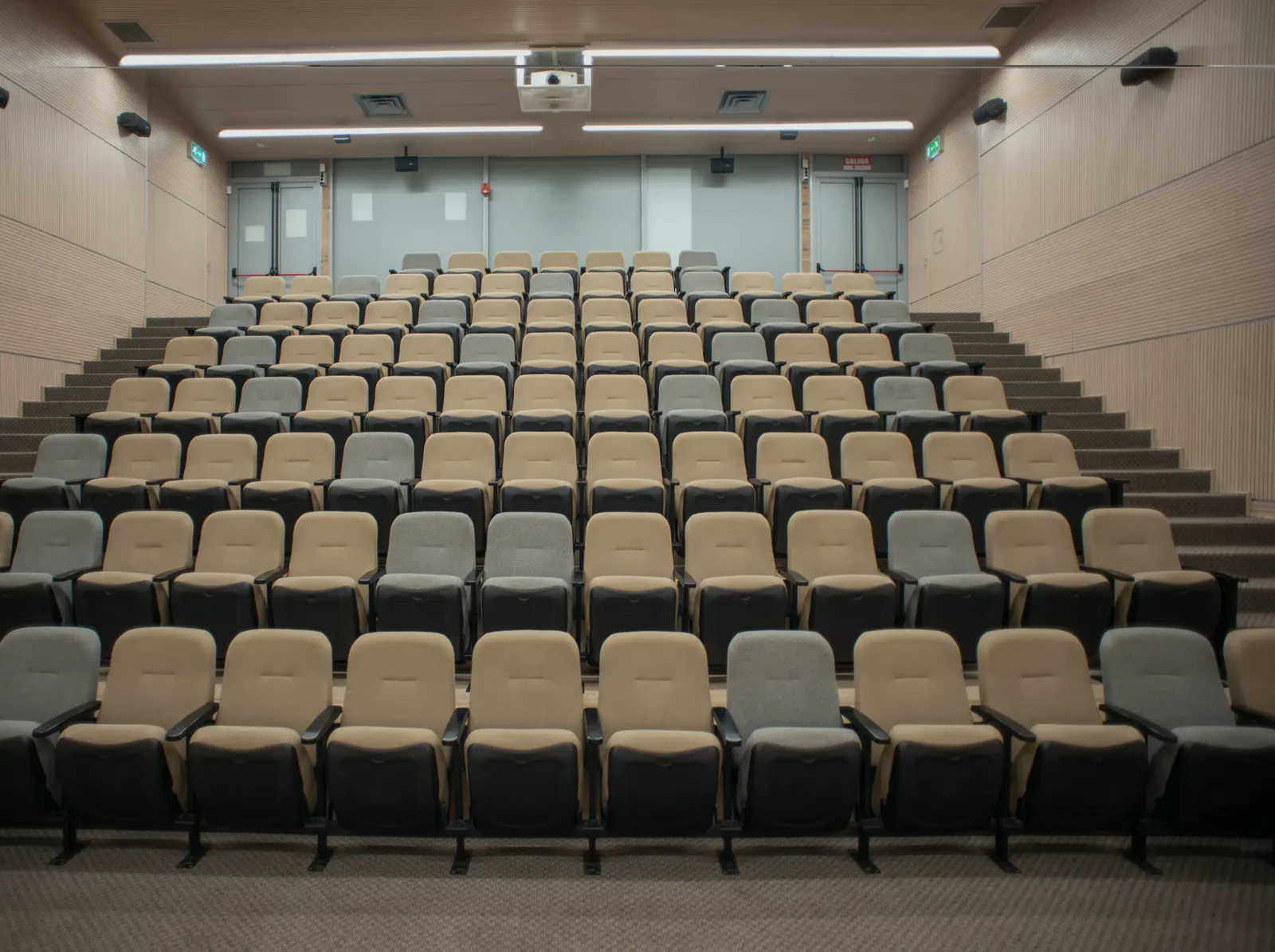 An empty lecture theatre, tiered seating, house lights on.